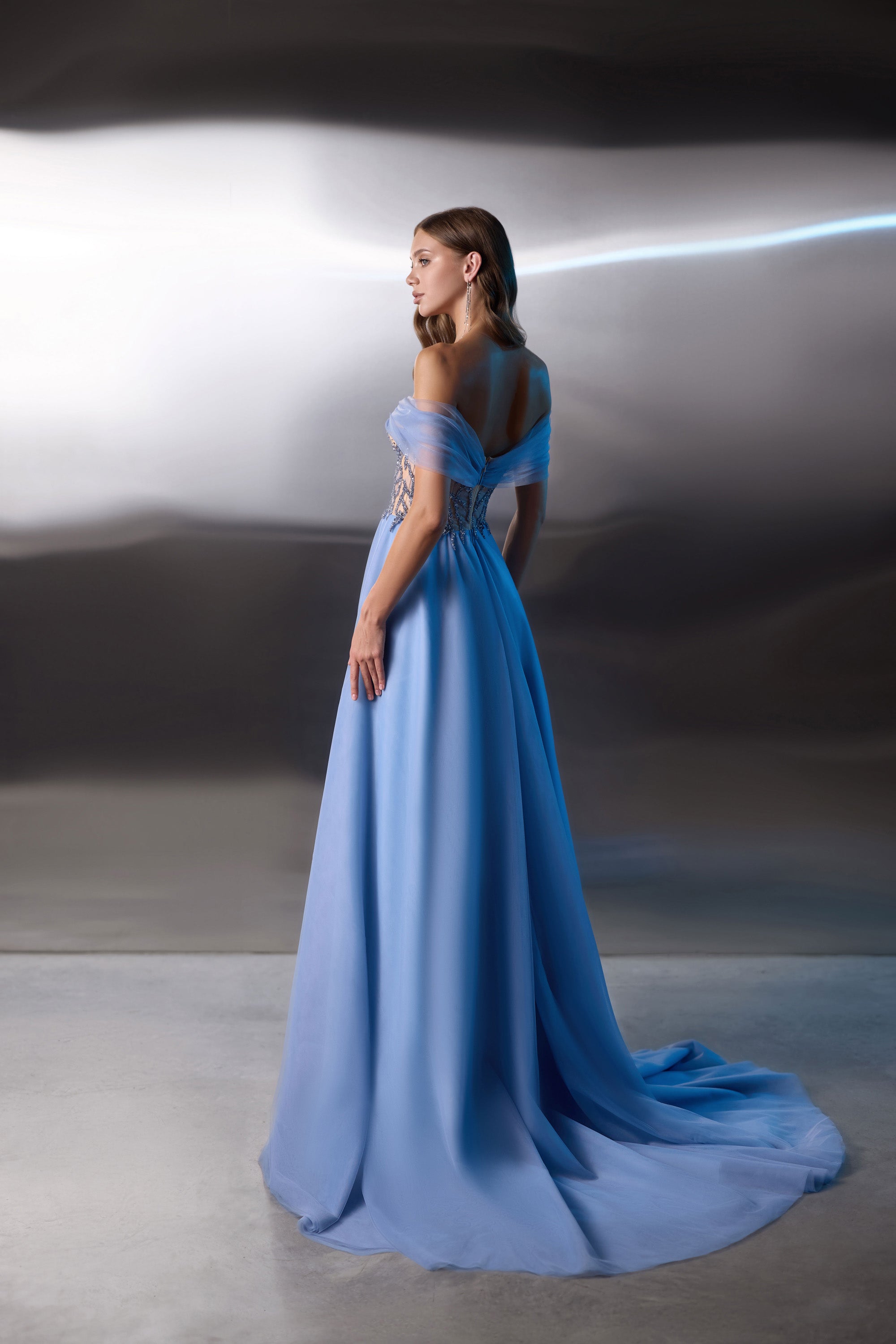 Blue evening dress with draped off-the-shoulder sleeves, a flowing skirt, and a long trailing train