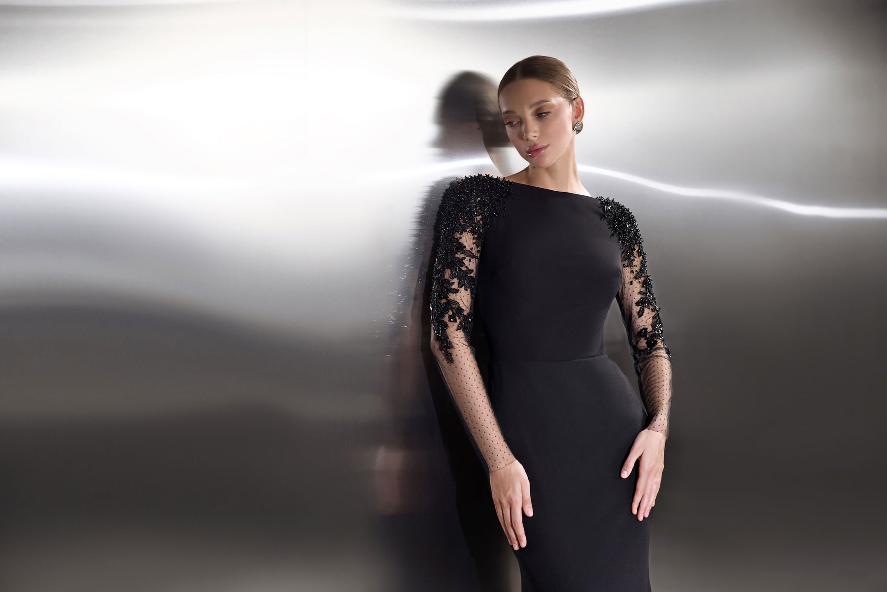 Close-up of a black evening dress with sheer floral lace sleeves and a high rounded neckline
