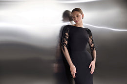 Close-up of a black evening dress with sheer floral lace sleeves and a high rounded neckline