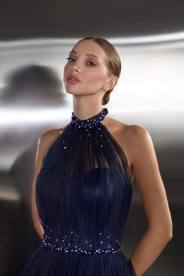 Navy evening dress with a sheer halter neckline, sparkling beadwork, and fitted embellished bodice
