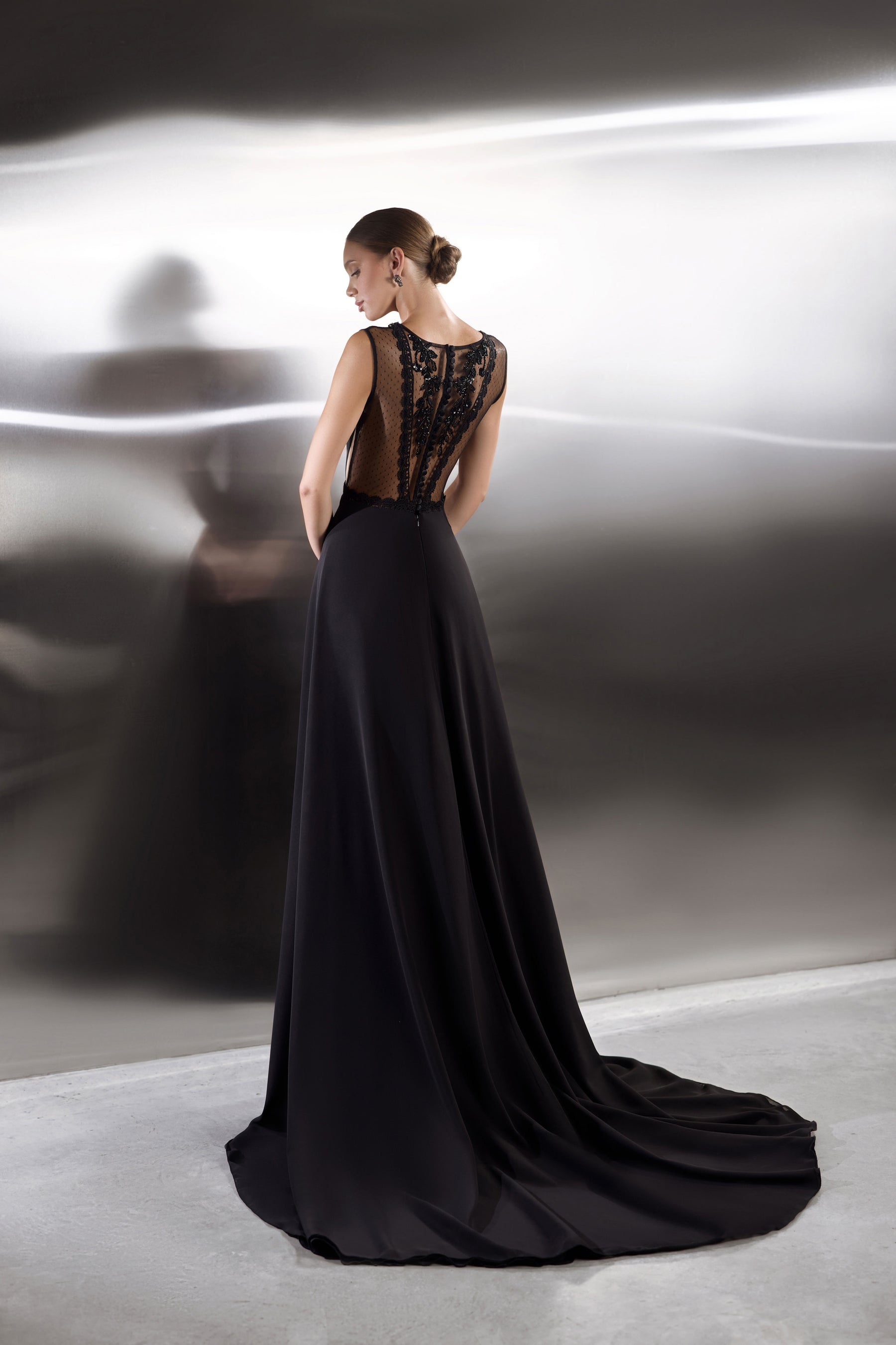 Black evening dress with an open lace back, sleeveless cut, flowing skirt, and long train