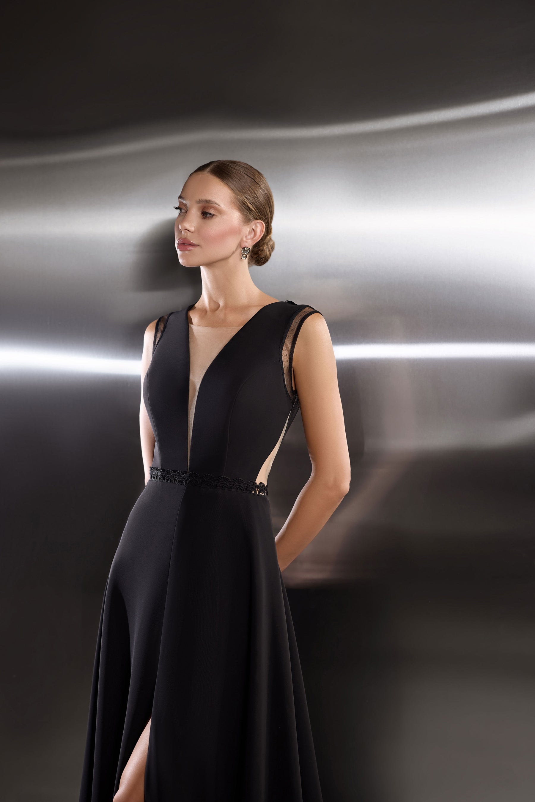 Black evening dress featuring a deep V-neckline, sheer side cutouts, and a beaded waist detail