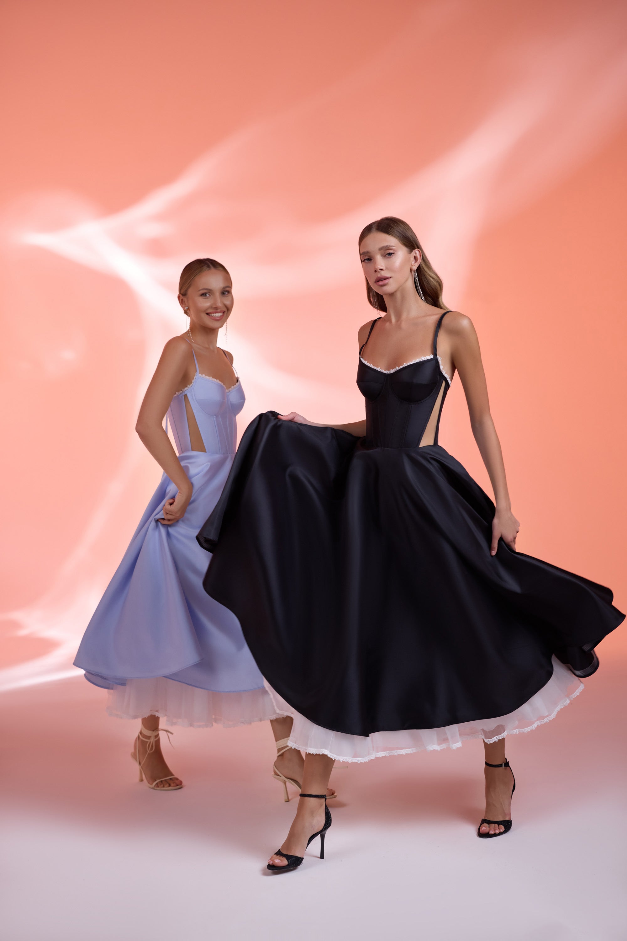 Black evening dress with thin straps, corset bodice, side cutouts, and a full satin skirt with tulle hem