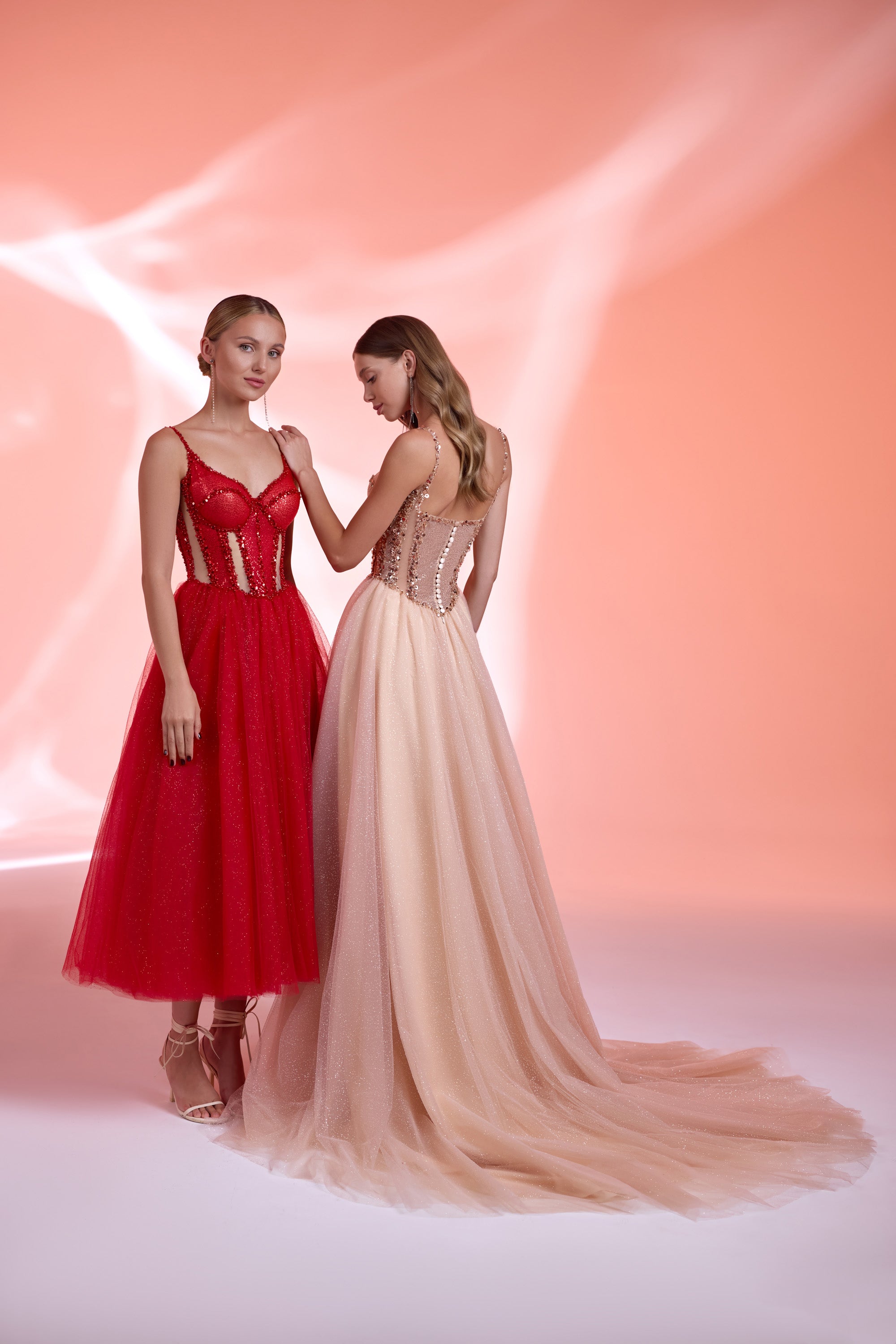 Back view of a blush evening dress with a beaded bodice, thin straps, flowing skirt, and long train