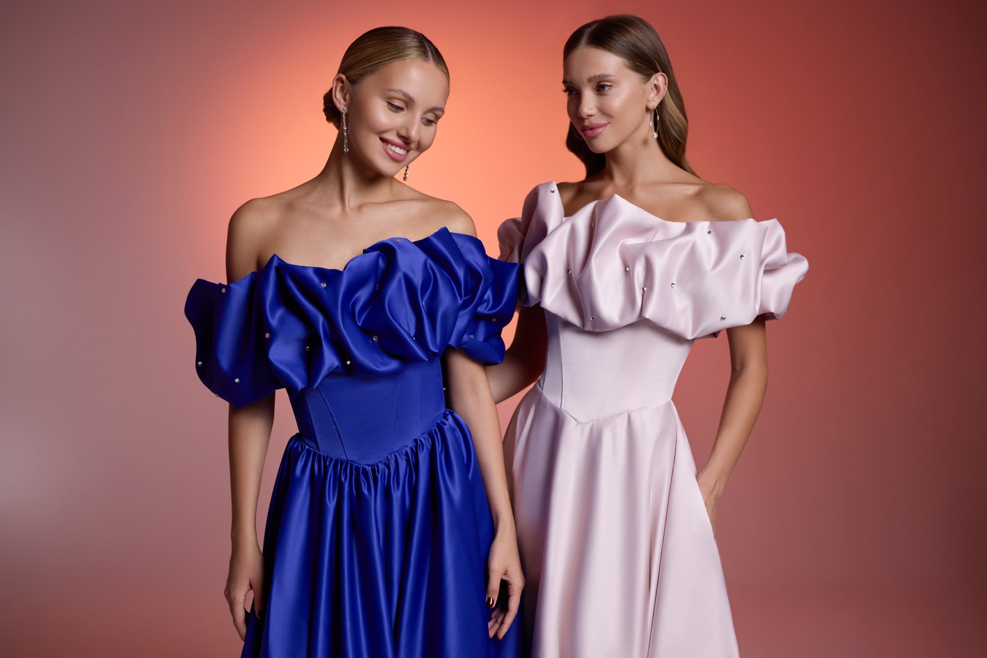 Close-up of a blush pink evening dress with crystal accents, an off-shoulder ruffled neckline, and fitted bodice
