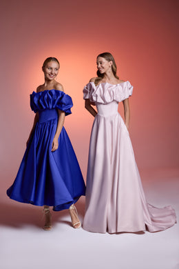 Floor-length blush pink evening dress with an off-shoulder ruffled neckline, fitted bodice, and trailing train