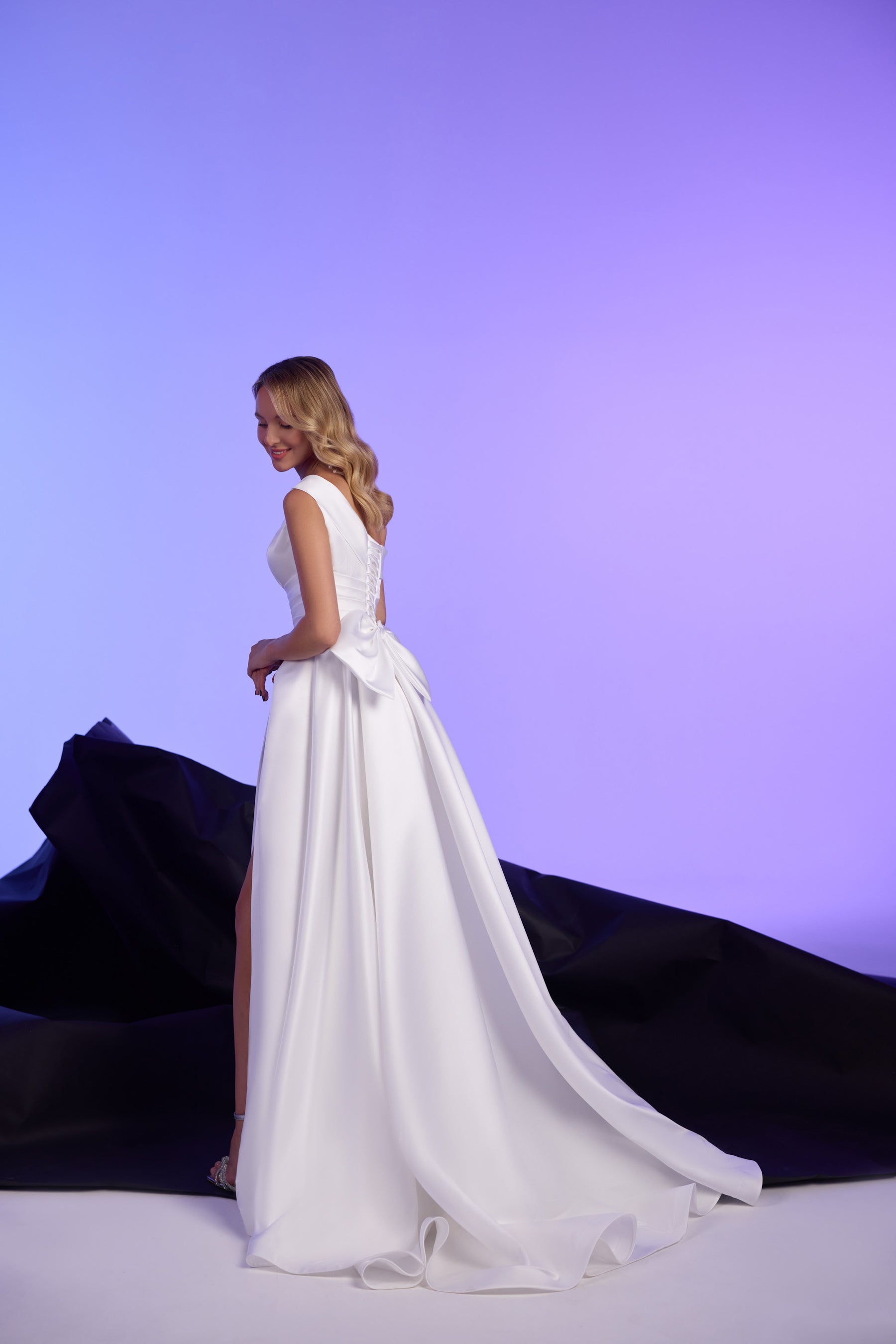 White evening dress with a fitted bodice, large back bow, and sweeping floor-length train