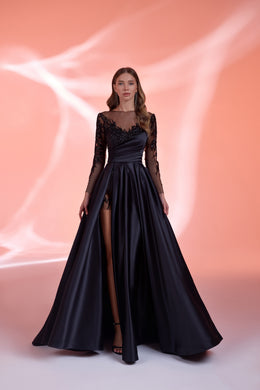 Black evening dress with a draped fitted bodice, sheer embellished sleeves, thigh-high slit, and full skirt