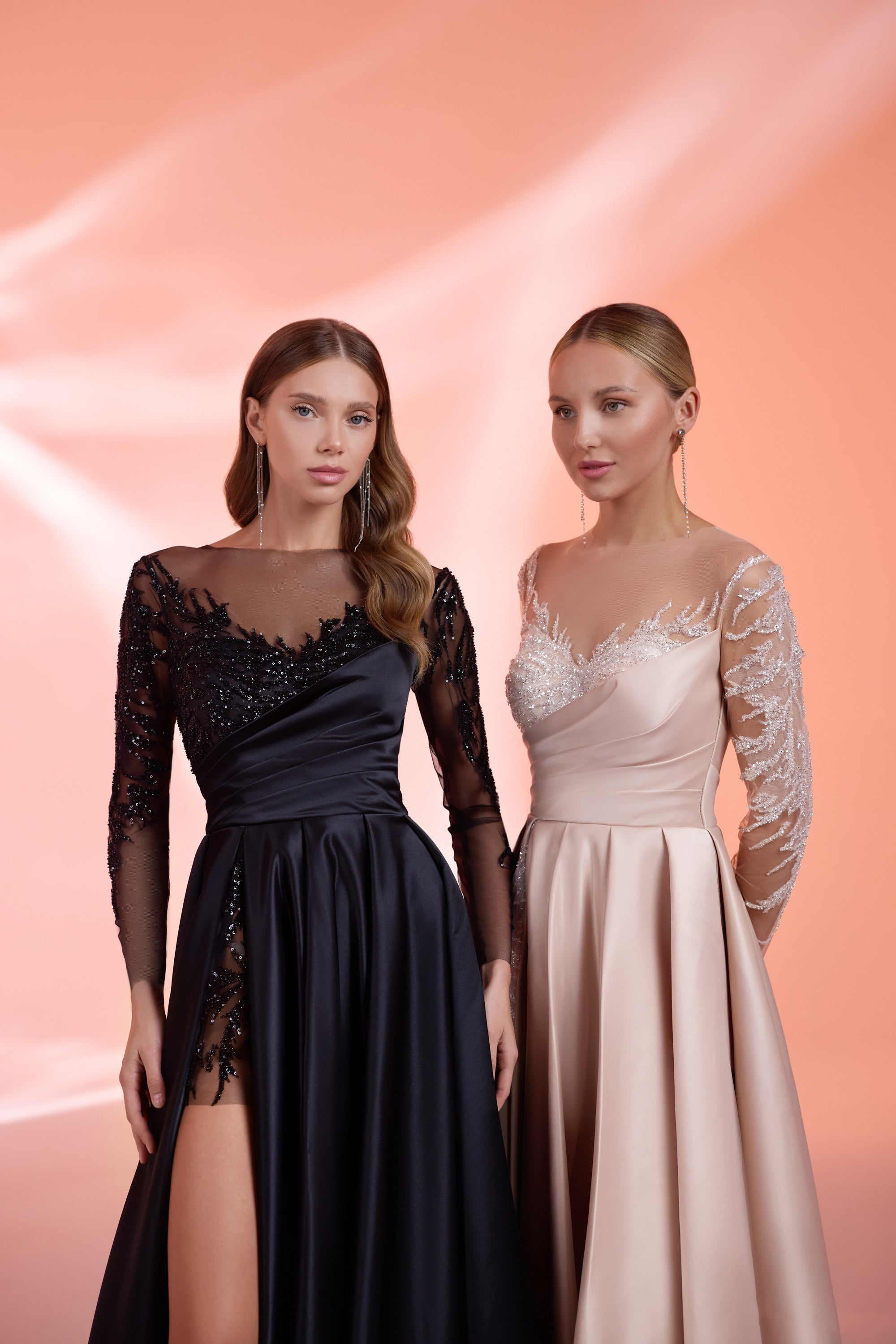 Close-up of a black evening dress with an illusion neckline, beaded sheer sleeves, and an asymmetrical slit