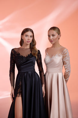 Close-up of a black evening dress with an illusion neckline, beaded sheer sleeves, and an asymmetrical slit