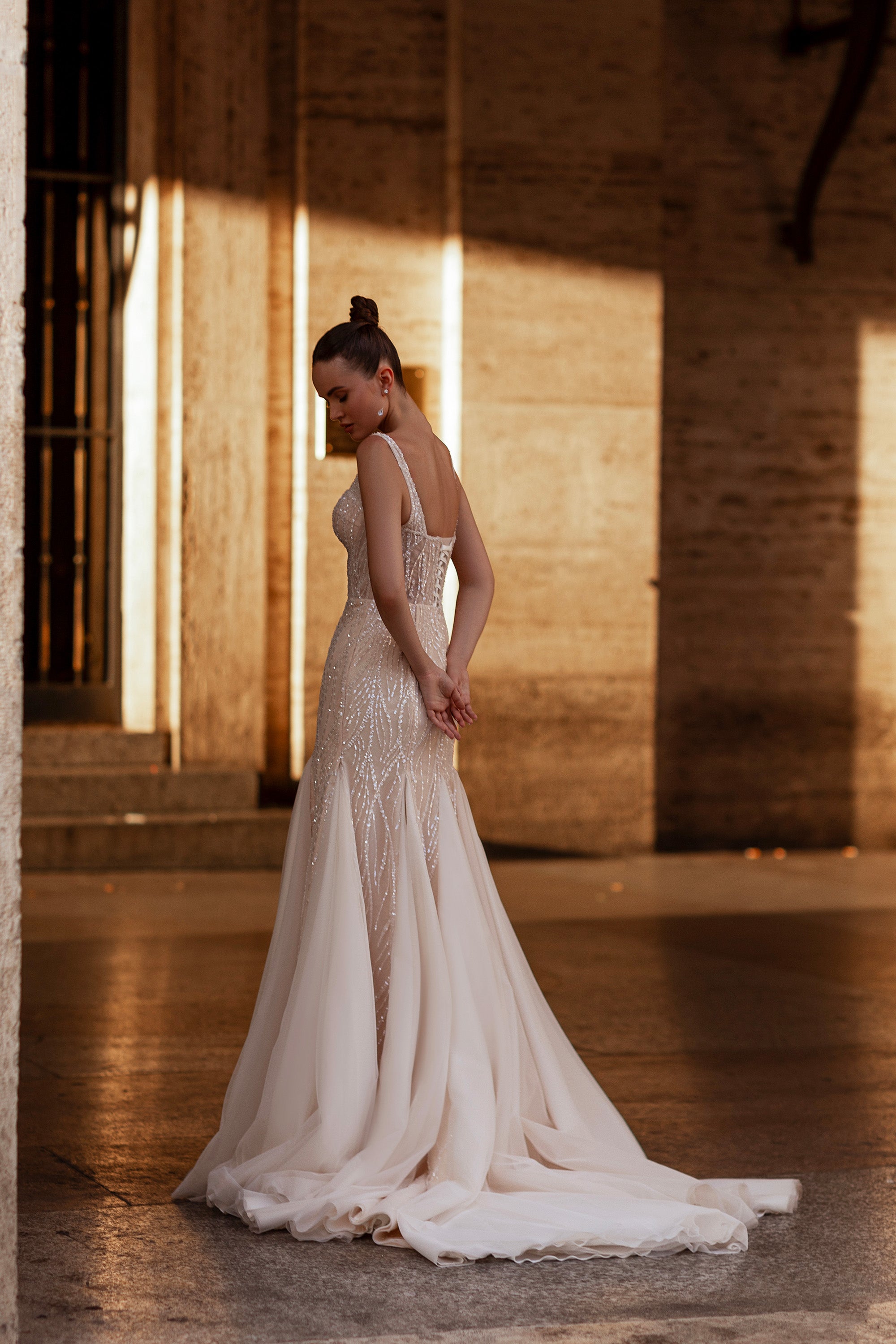 Beaded ivory wedding dress with an open back, sheer cape, fitted trumpet skirt, and long train