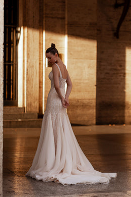 Beaded ivory wedding dress with an open back, sheer cape, fitted trumpet skirt, and long train