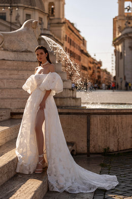 White wedding dress with off-the-shoulder puff sleeves, a high slit, floral texture, and a long train