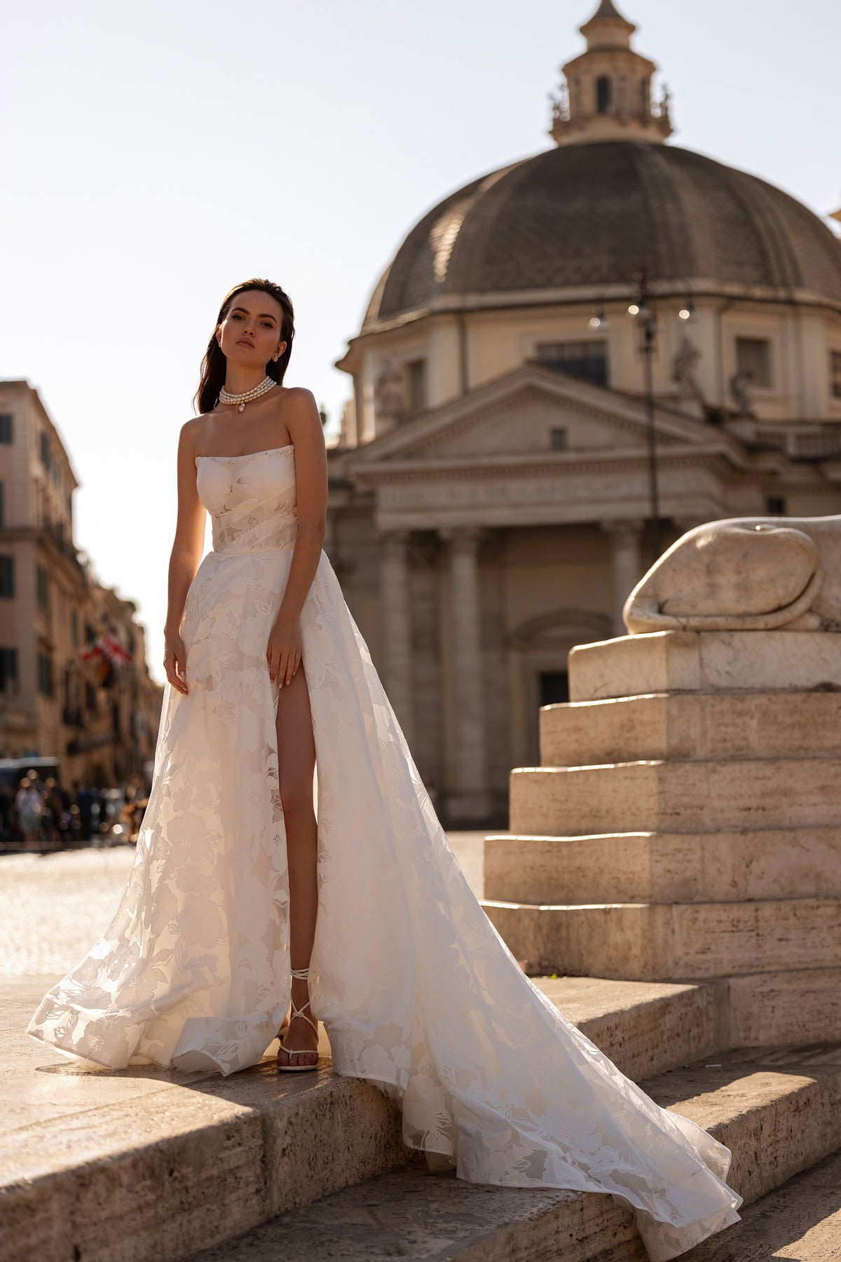 White wedding dress with a fitted bodice, thigh-high slit, floral texture, and a long trailing train