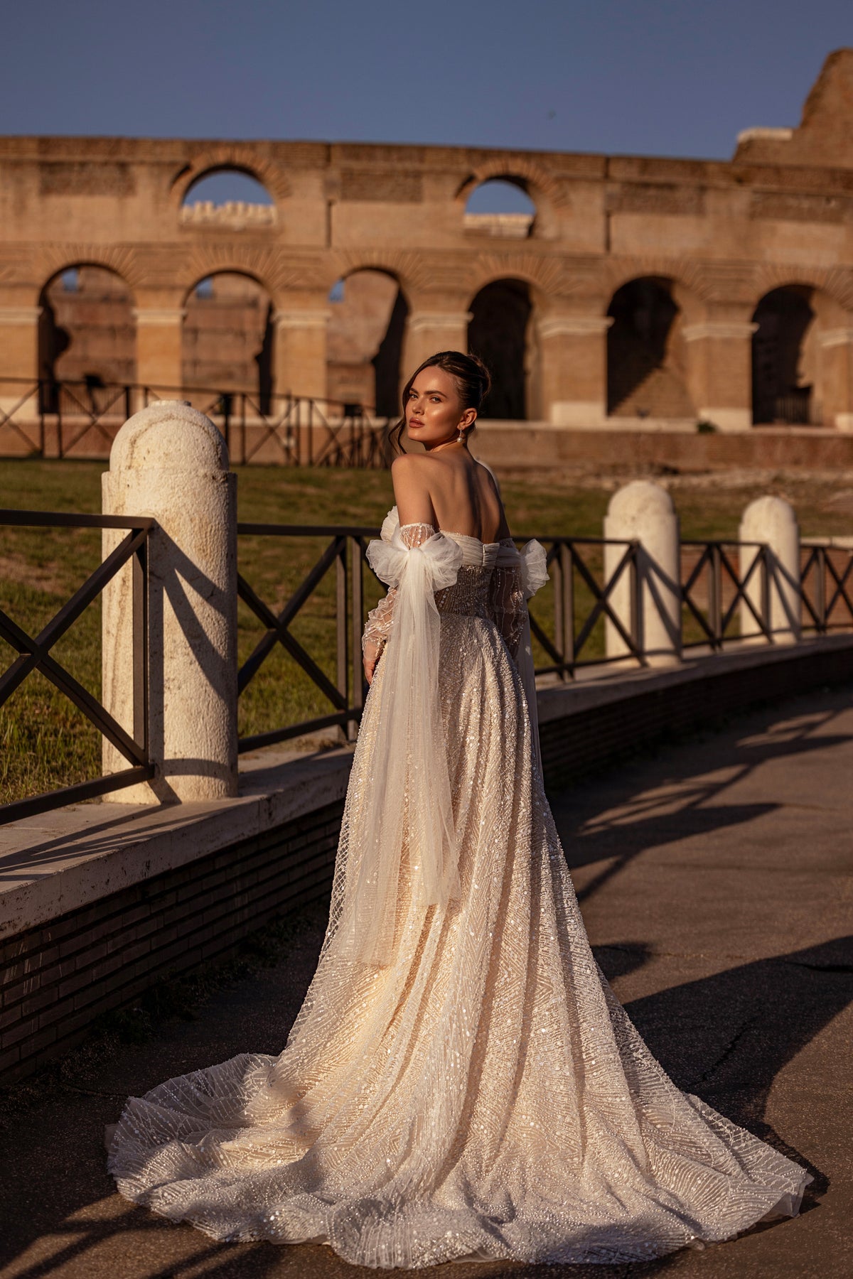Low open back and sweeping train on a sparkling ivory wedding dress with sheer detachable sleeves