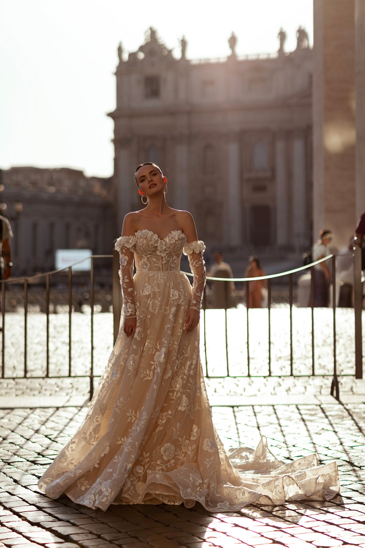 A-line ivory wedding dress with an off-the-shoulder neckline, sheer sleeves, and floral appliqués