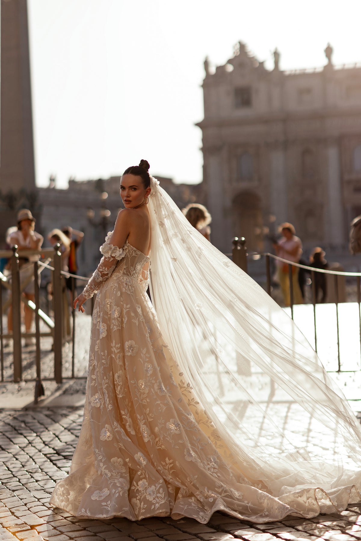 Ivory wedding dress with floral appliqués, sheer long sleeves, and a sweeping lace train
