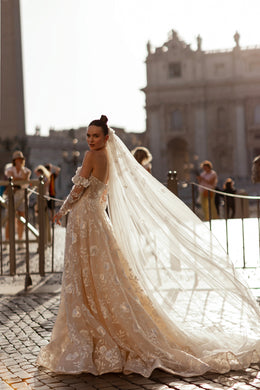 Ivory wedding dress with floral appliqués, sheer long sleeves, and a sweeping lace train