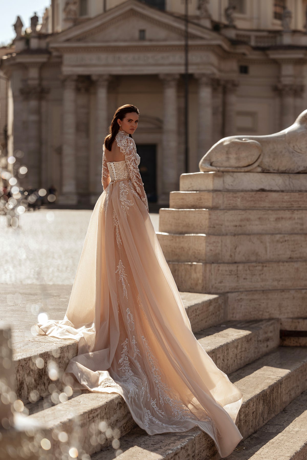 Ivory wedding dress showing a sweeping sheer overskirt, lace detailing, and long embellished train
