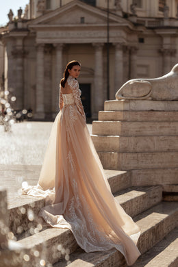 Ivory wedding dress showing a sweeping sheer overskirt, lace detailing, and long embellished train
