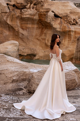 Side view of an ivory wedding dress with a low open back, flowing A-line skirt, and sweeping train