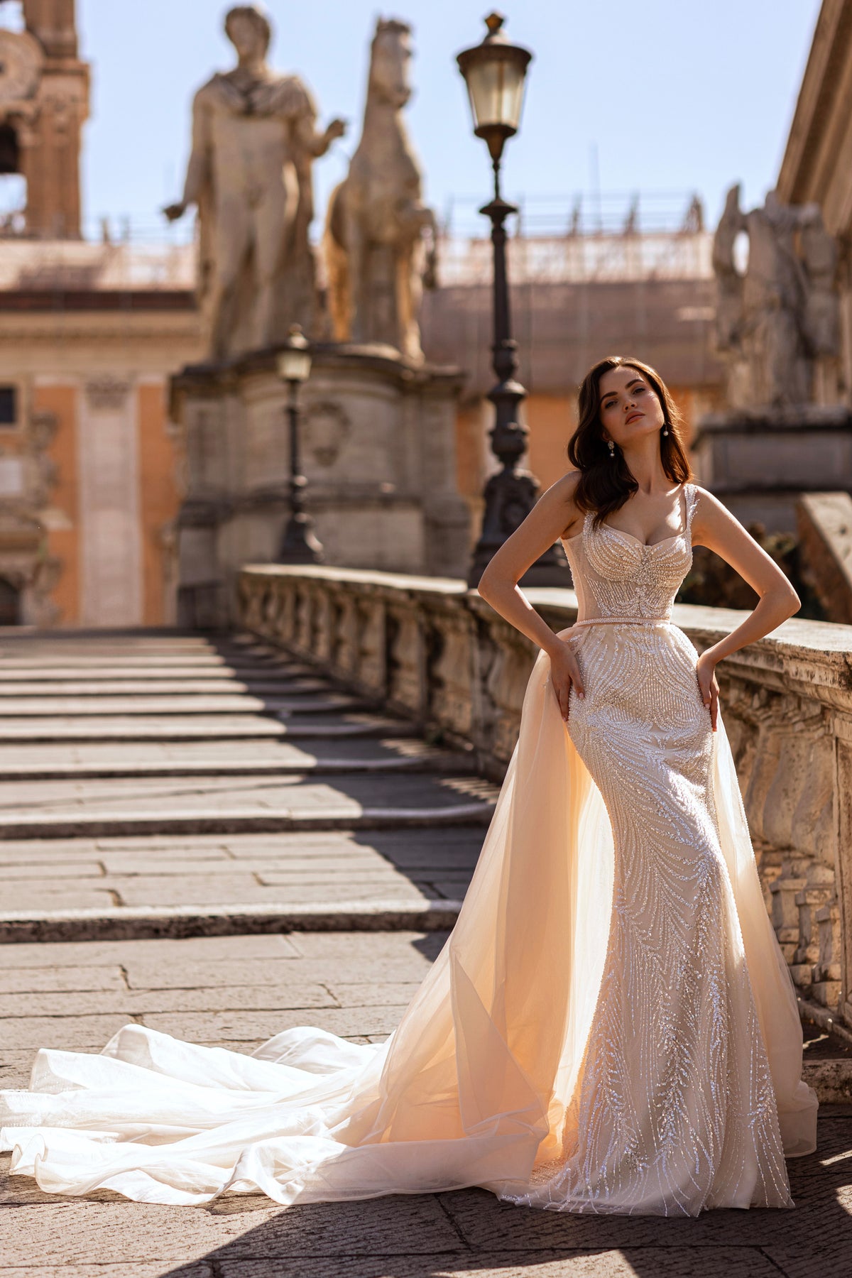 Beaded ivory wedding dress with a fitted silhouette, scoop neckline, and detachable tulle overskirt and train