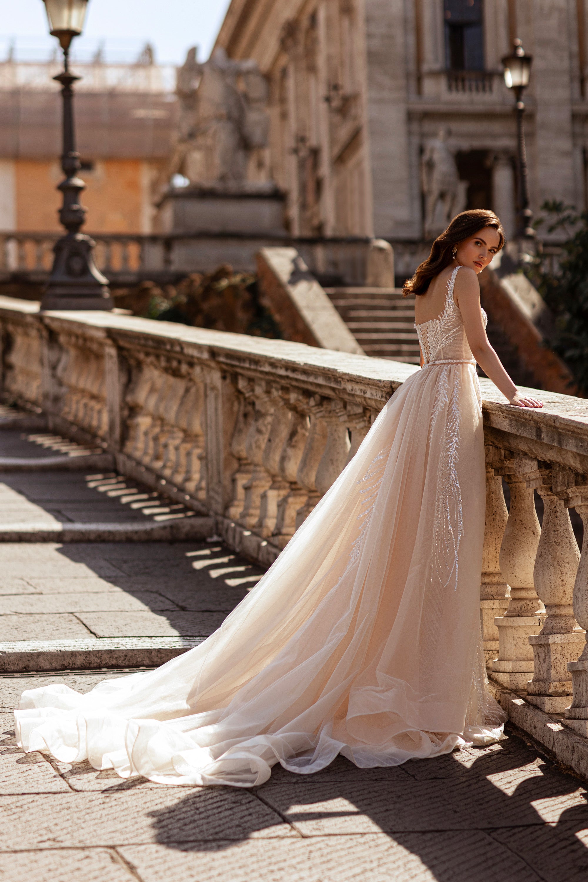 Open-back ivory wedding dress with a beaded bodice, fitted waist, and long sheer tulle train