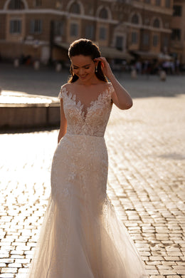 Beaded ivory wedding dress with a sheer illusion neckline, short sleeves, fitted waist, and mermaid skirt