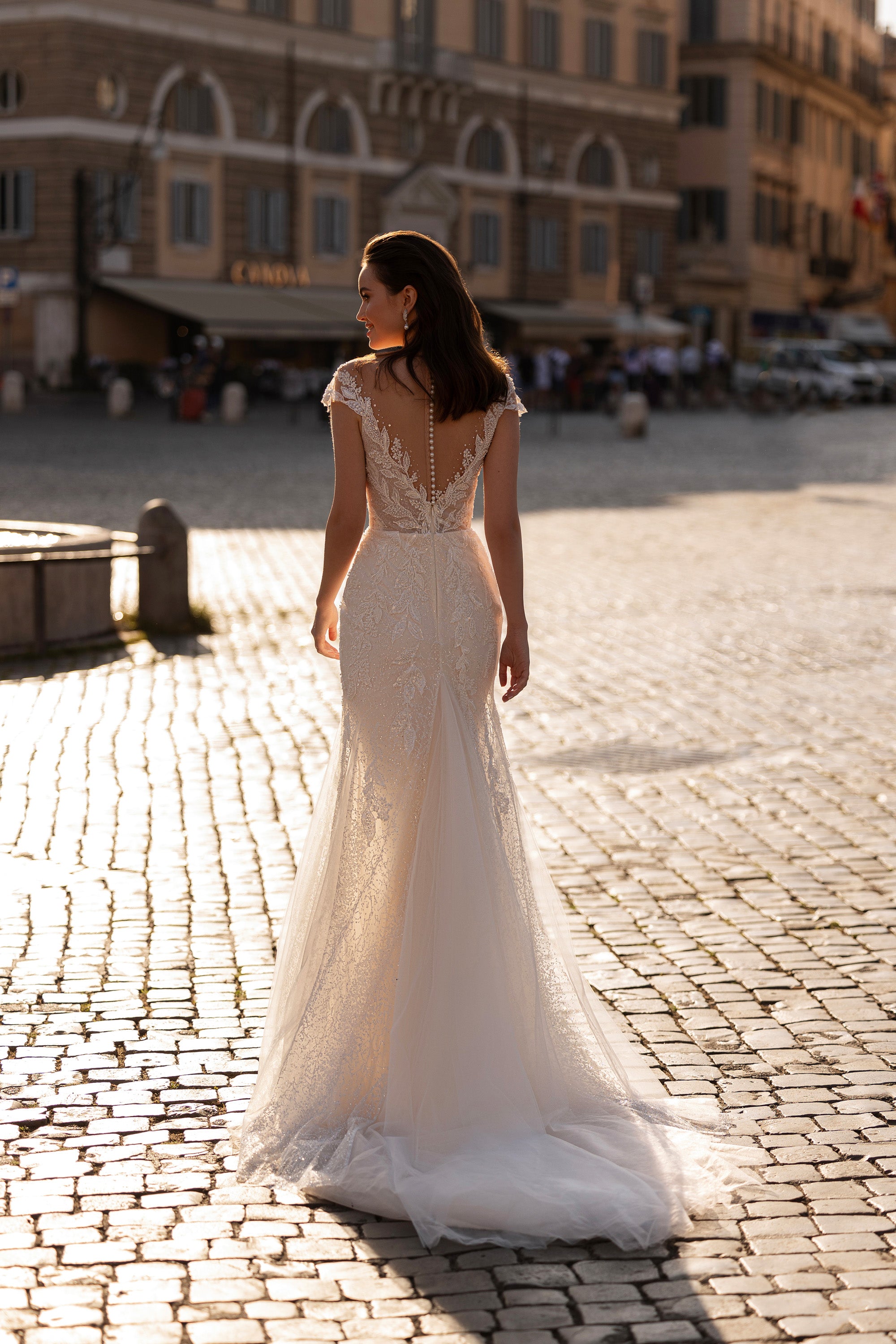 Back view of an ivory mermaid wedding dress featuring an open illusion back, beaded lace, and long train
