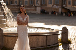 Ivory mermaid wedding dress showcasing beadwork, a sheer neckline, short sleeves, and flowing train