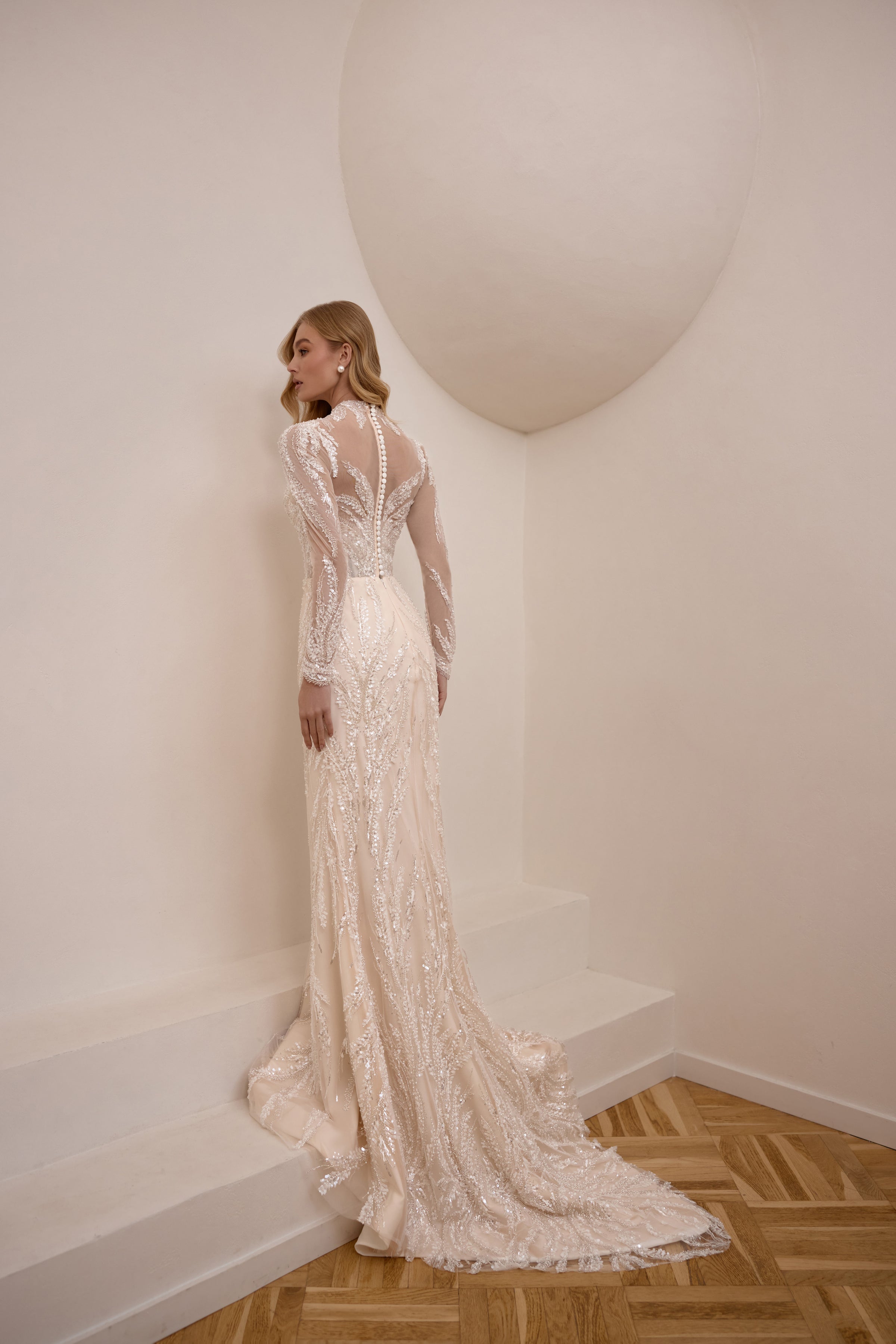 Beaded ivory wedding dress with a sheer V-back, long sleeves, and a dramatic floor-length train