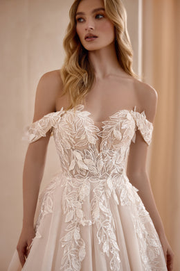 Close-up of an ivory wedding dress bodice with off-the-shoulder sleeves and layered floral lace appliqués