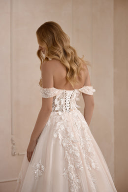 Corset-style lace-up back and off-the-shoulder sleeves on an ivory wedding dress with floral appliqués