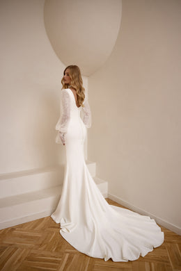 Buttoned back and sweeping train on an ivory sheath wedding dress with sheer lace bishop sleeves