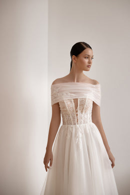 Ivory wedding dress featuring a draped off-the-shoulder neckline, corset-style lace bodice, and flowing A-line skirt