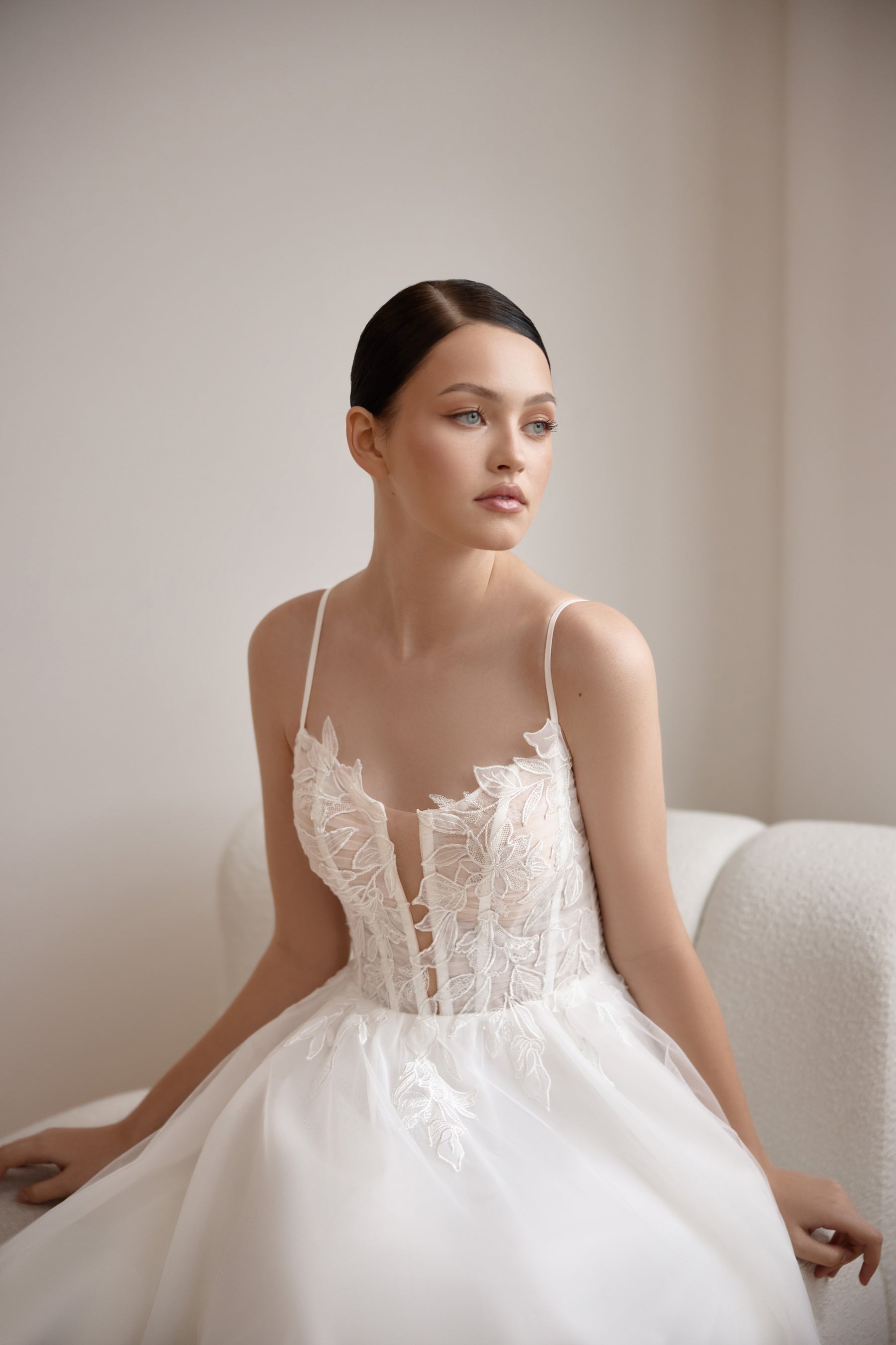 Close-up of an ivory wedding dress with thin straps, floral lace appliqués, and a structured corset bodice