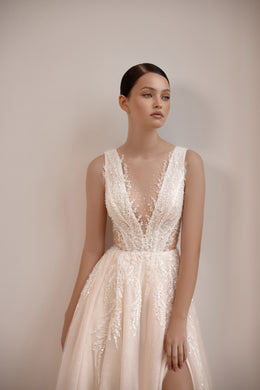 Close-up of a deep illusion V-neck and sparkling lace bodice on a blush wedding dress