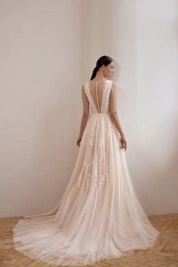 Sheer illusion back with lace detailing, A-line skirt, and long train on a blush wedding dress