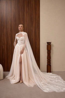 Blush A-line wedding dress with floral lace corset, sheer cape, thigh-high slit, and sweeping embellished train