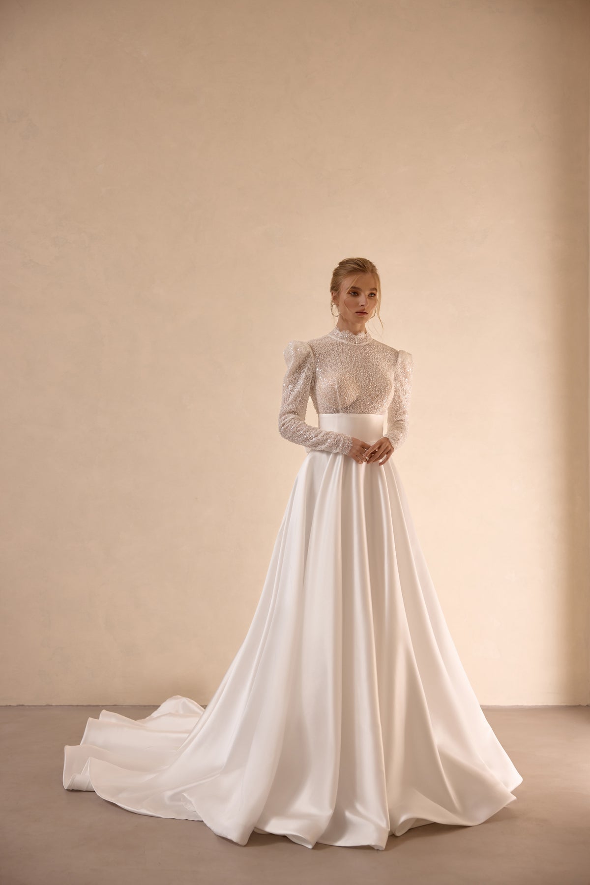 Ivory A-line wedding dress with a high neck, sparkling long sleeves, full skirt, and sweeping train