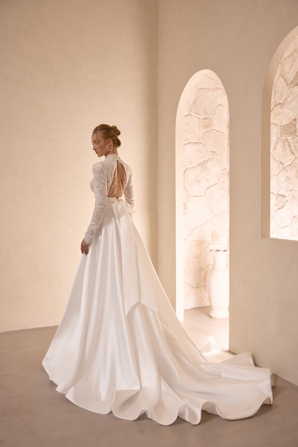 Ivory wedding dress with an open back, beaded straps, flowing A-line skirt, and extended train