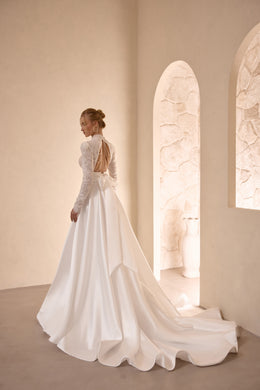 Ivory wedding dress with an open back, beaded straps, flowing A-line skirt, and extended train