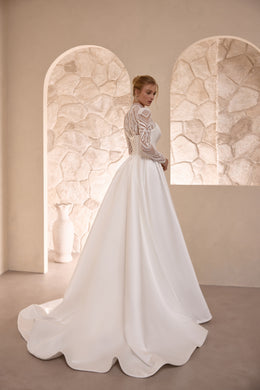 Three-quarter back view of an ivory wedding dress with lace sleeves and a sweeping satin train