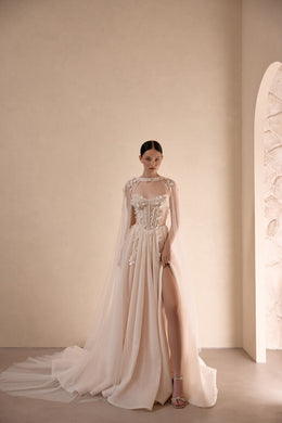 Ivory wedding dress with a beaded corset bodice, high slit, and sheer flowing cape