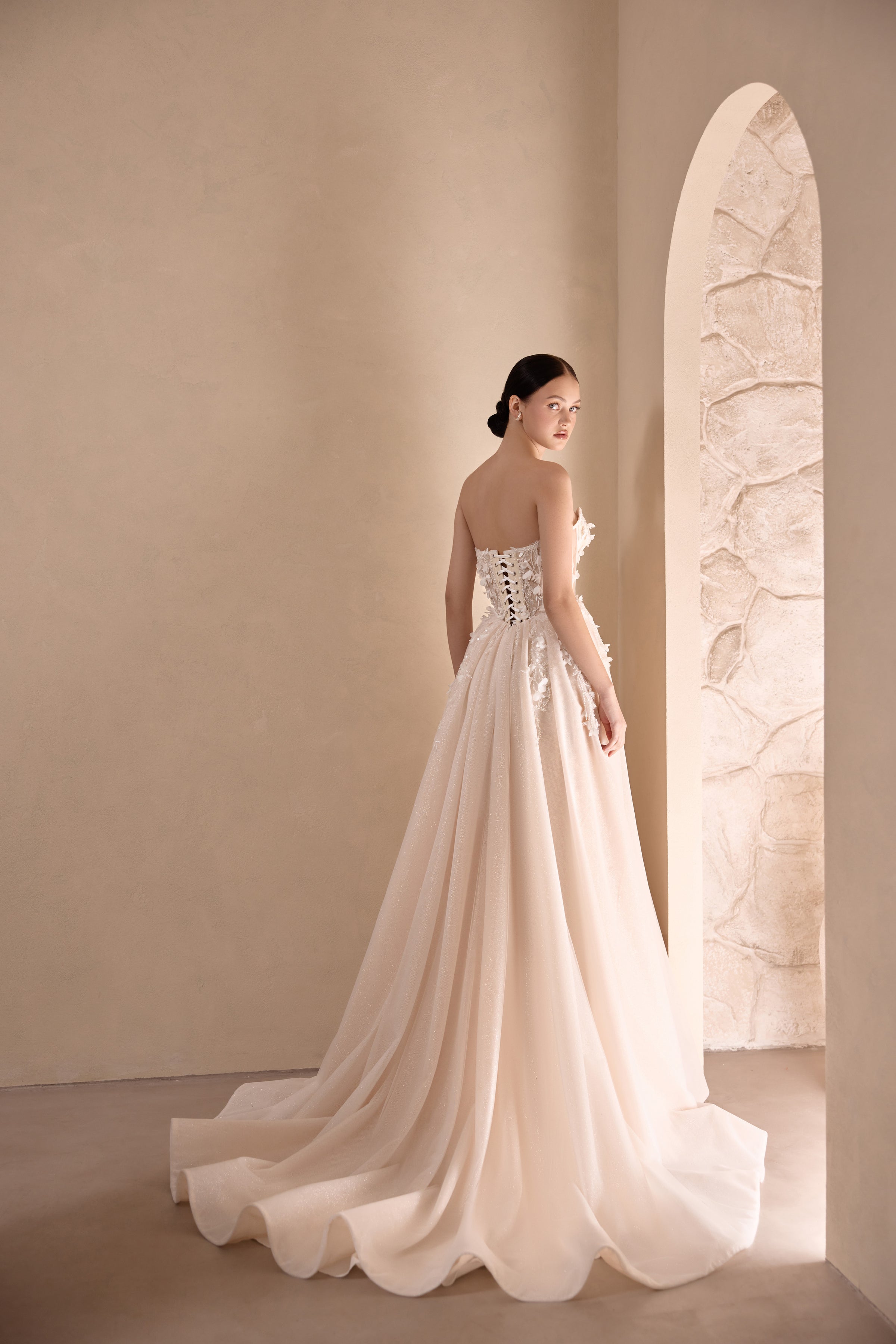 Strapless ivory wedding dress with an embellished back, full flowing skirt, and scalloped train