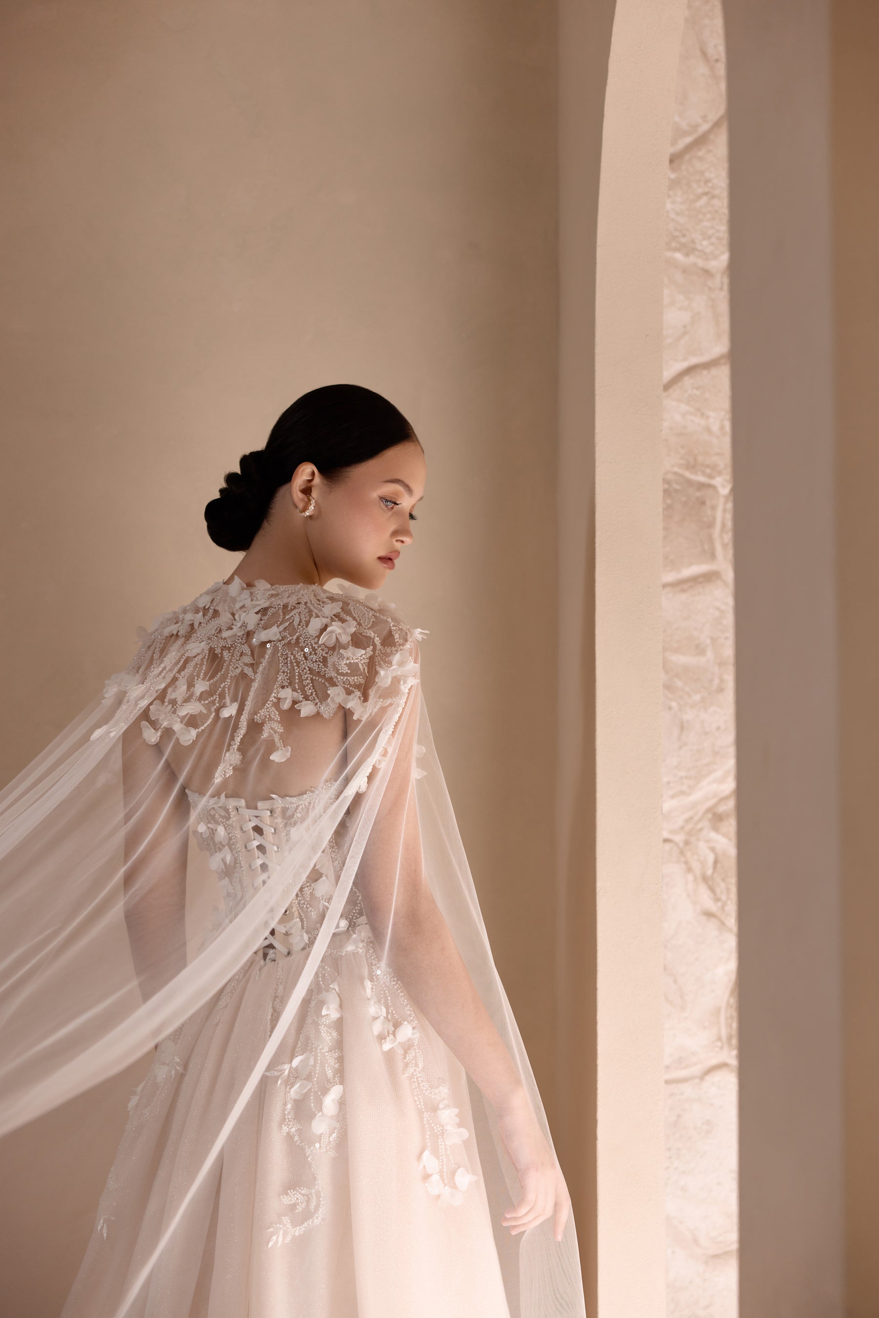Close-up of a sheer floral-embroidered cape draped over an ivory wedding dress