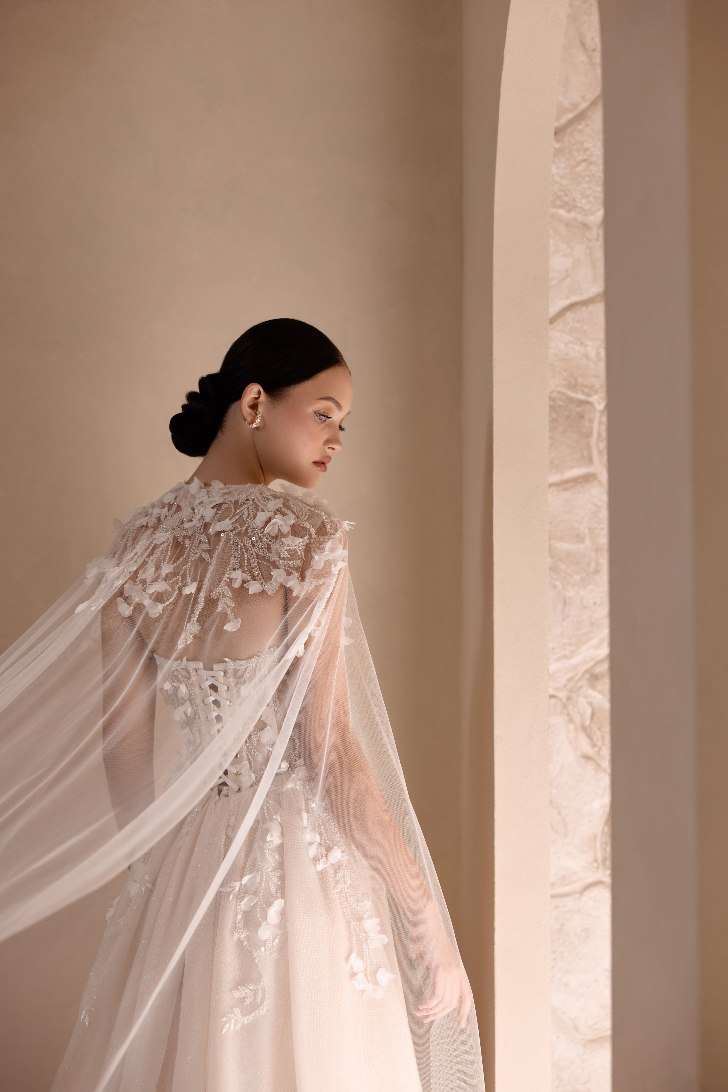 Close-up of a sheer floral-embroidered cape draped over an ivory wedding dress
