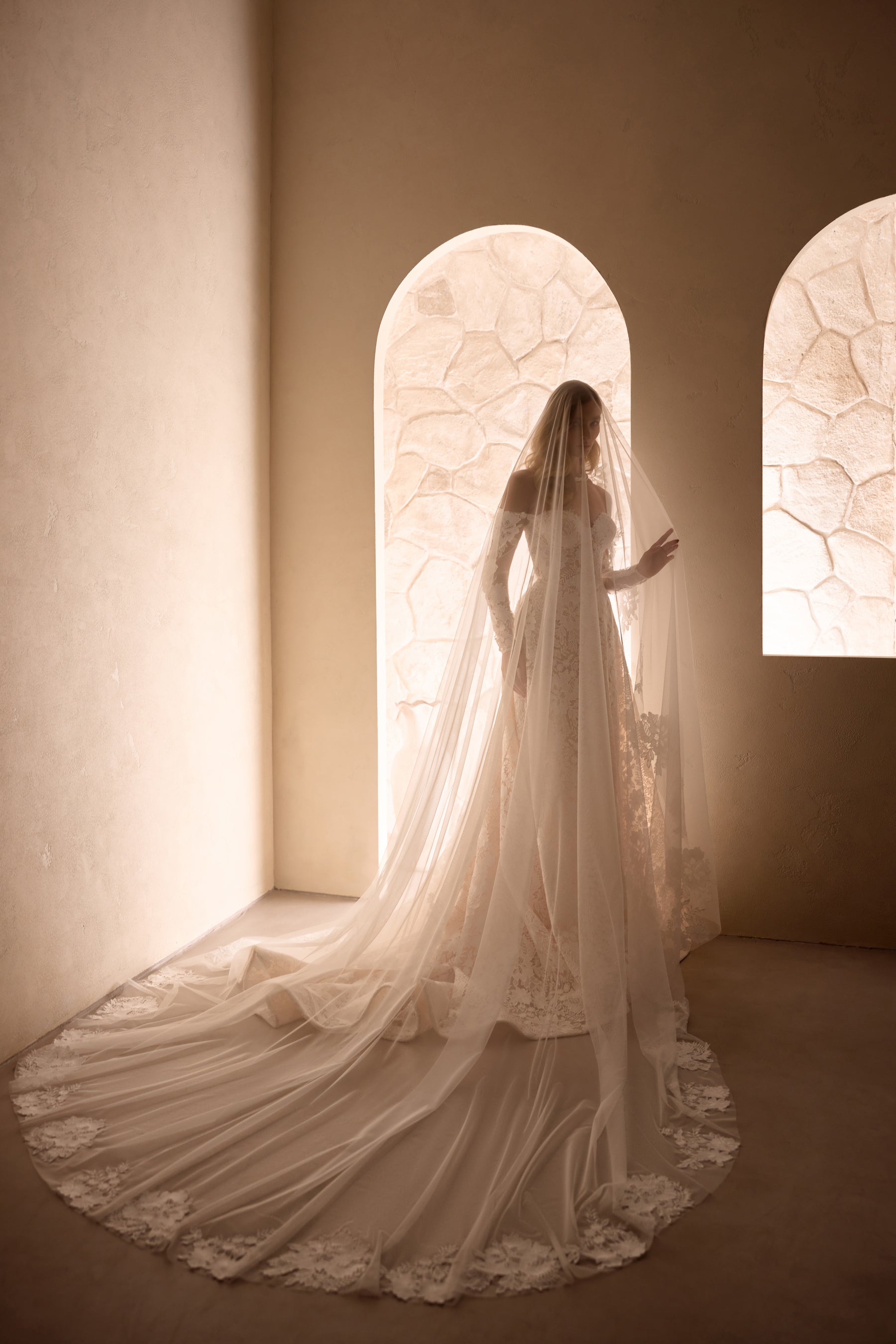 Rear view of an ivory wedding dress with a long lace-edged veil and extended flowing train