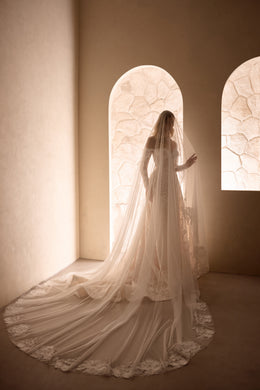 Rear view of an ivory wedding dress with a long lace-edged veil and extended flowing train