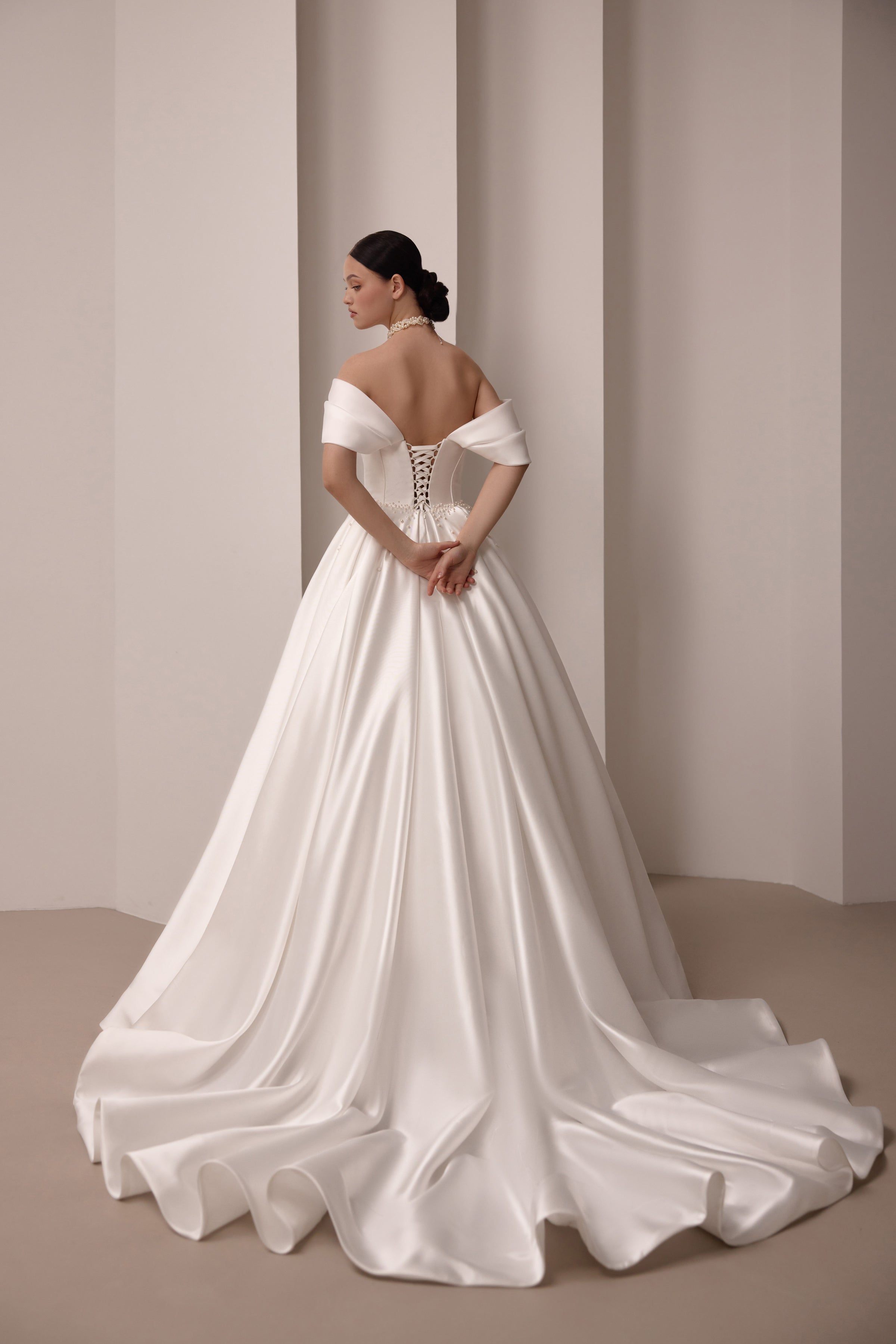 Lace-up corset back and sweeping satin train on an ivory off-the-shoulder wedding dress